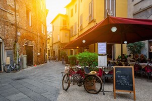 A narrow street with a café, outdoor seating, and a bicycle parked by the entrance.