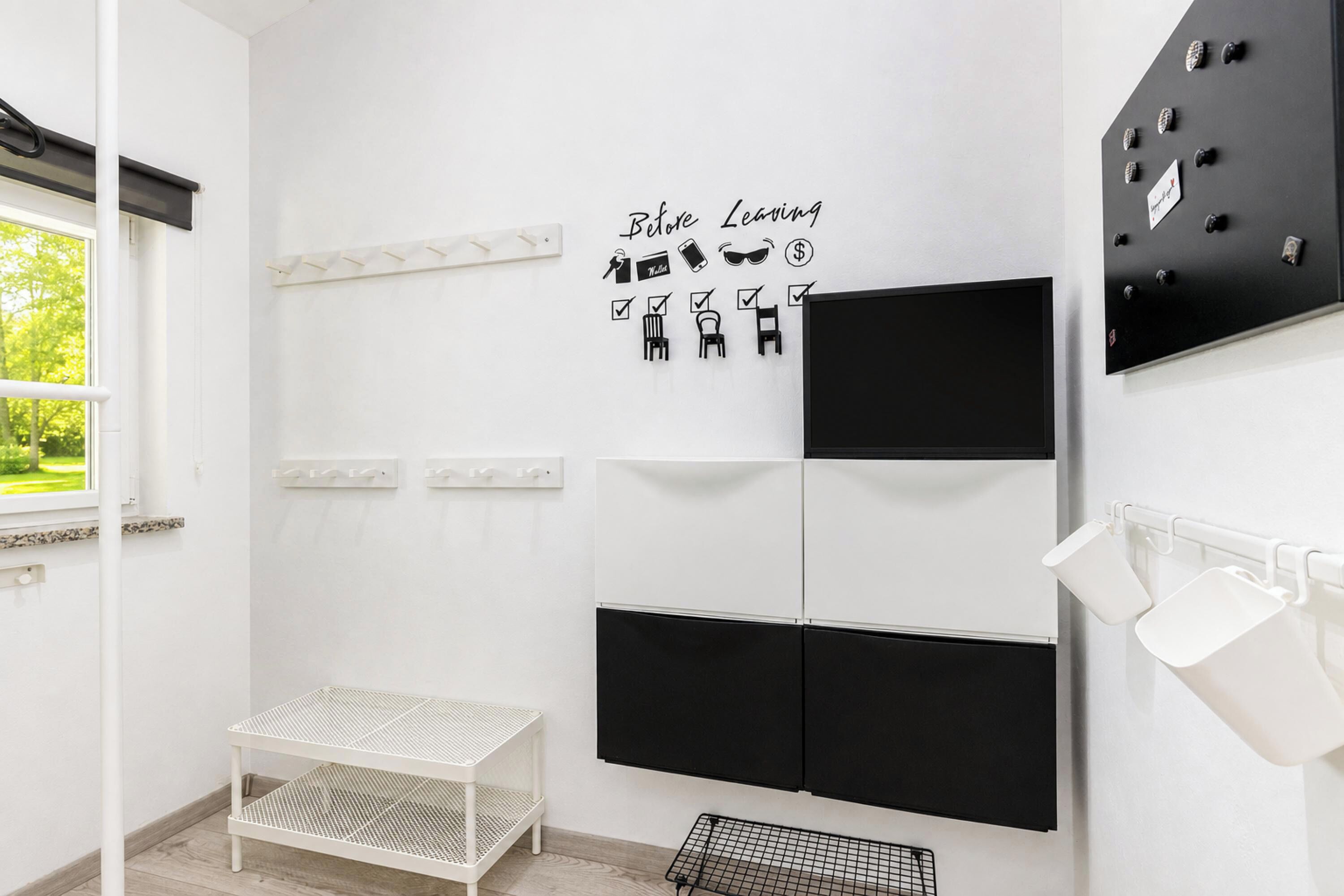 Un baño moderno con una paleta de colores blanco y negro, una lista de verificación 'Antes de Irse' y una ventana con vistas a la vegetación.