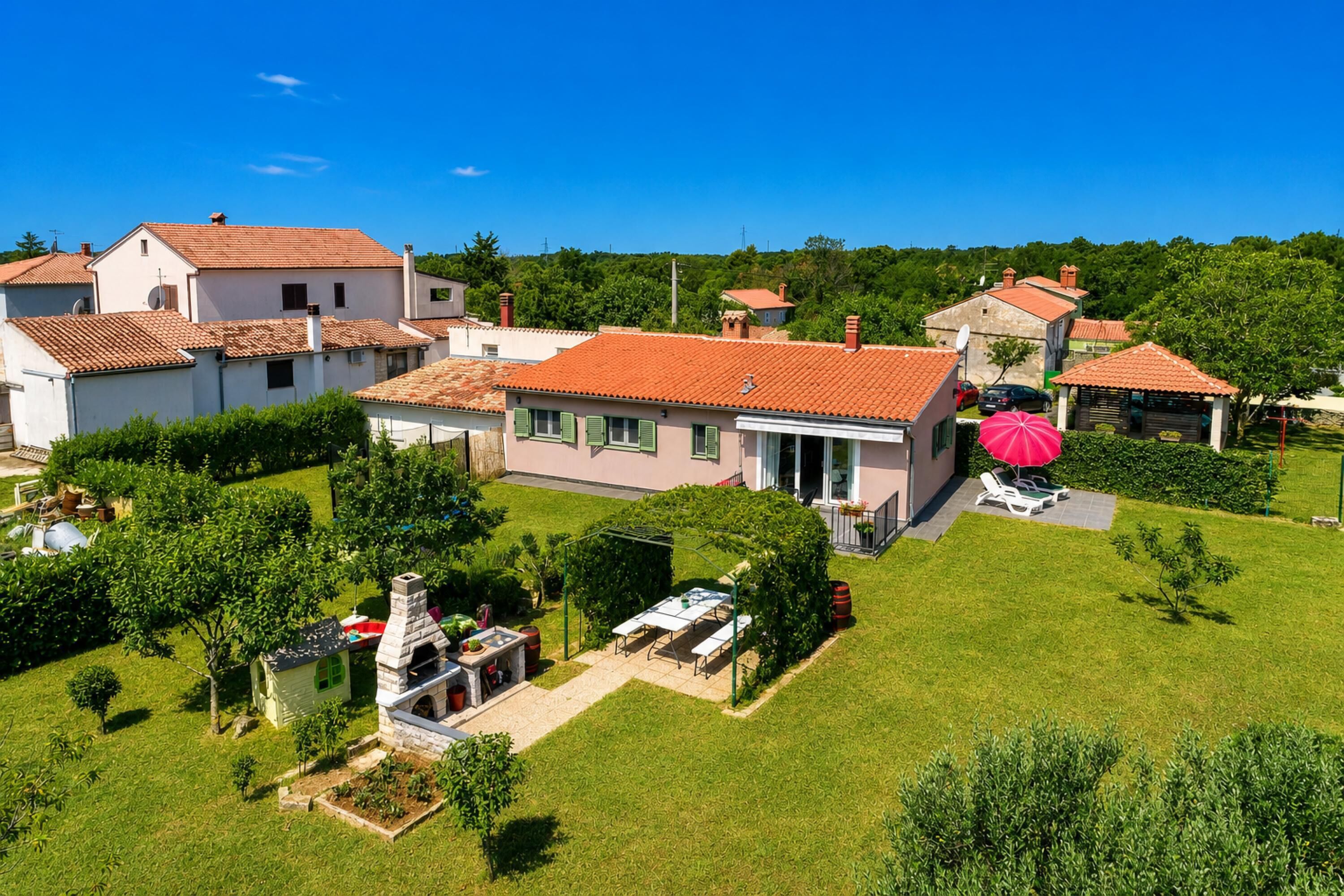 Zona residencial con casas, un pequeño jardín y un paraguas rojo.