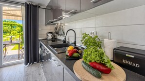 A modern kitchen with a large window, a sink, and a countertop with fresh vegetables. - Family Friendly House Kacana - Garden & BBQ (Vodnjan)