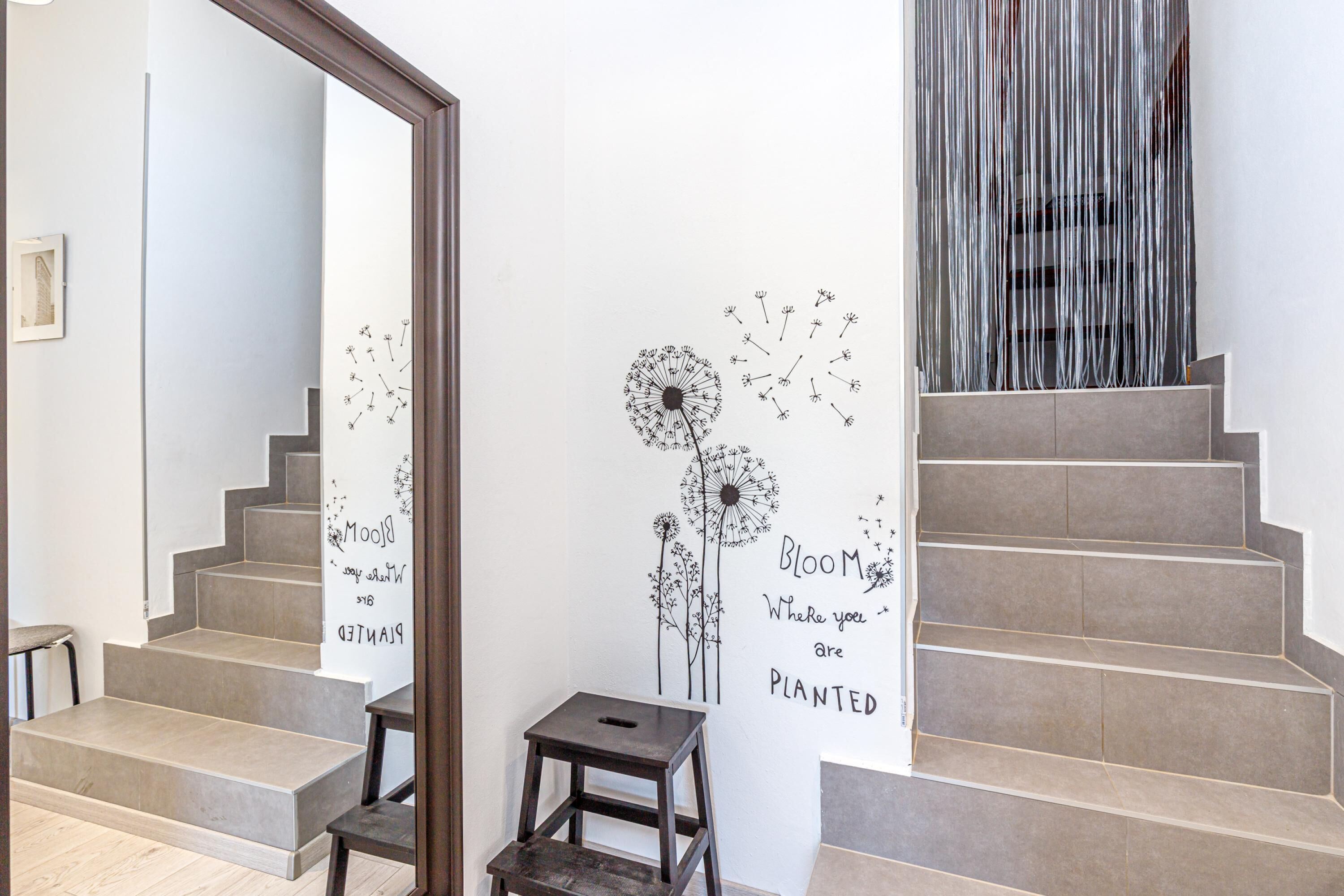 Eine Treppe mit Wandgemälde, das Löwenzahn und motivierende Schriftzüge zeigt.