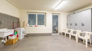 A bathroom with a sink, mirror, toilet, and a window. There are plastic chairs and a cabinet with a mirror. - Casa Luminosa Ski in -Ski out 100m (Livigno)