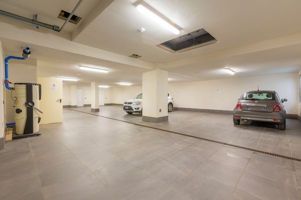 A parking garage with multiple levels, a ventilation system, and a few parked cars. - Casa Luminosa Ski in -Ski out 100m (Livigno)