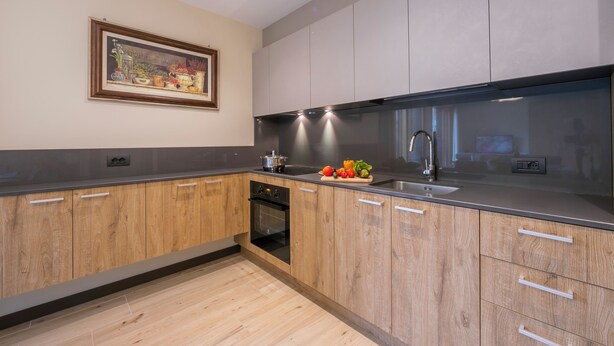 A modern kitchen with wooden cabinets, a stainless steel sink, and a built-in oven. - Casa Luminosa Ski in -Ski out 100m (Livigno)
