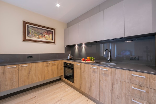 A modern kitchen with wooden cabinets, a stainless steel sink, and a built-in oven. - Casa Luminosa Ski in -Ski out 100m (Livigno)