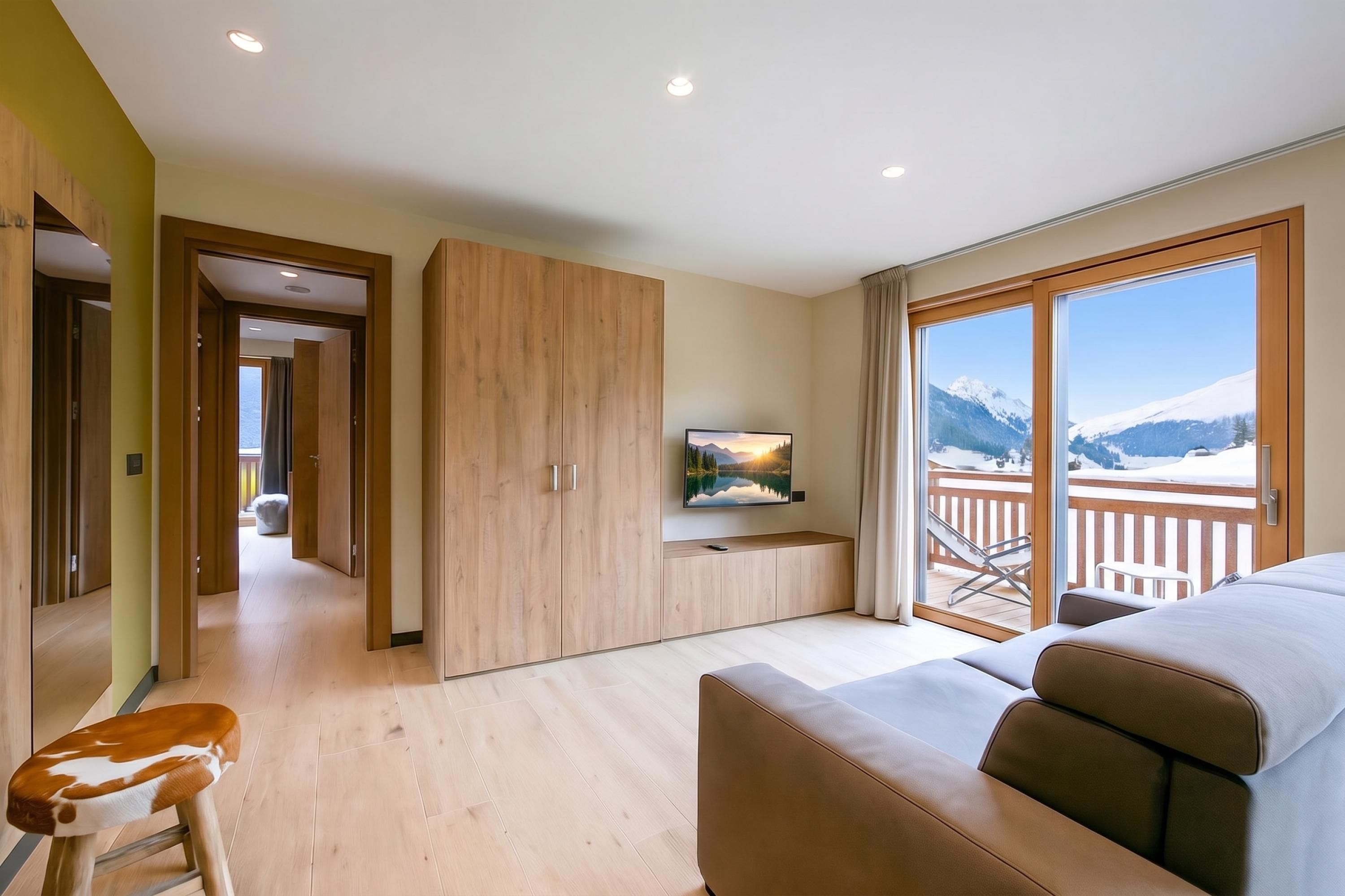 Ein Hotelzimmer mit großem Fenster, einer Couch, einem Fernseher und einem Holzschrank.
