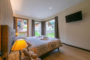 Une chambre à coucher avec un lit, une lampe, un jouet en peluche et un téléviseur fixé au mur.