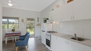 Eine moderne Küche mit weißen Schränken, einer Edelstahlspüle und einem Essbereich mit Tisch und Stühlen.