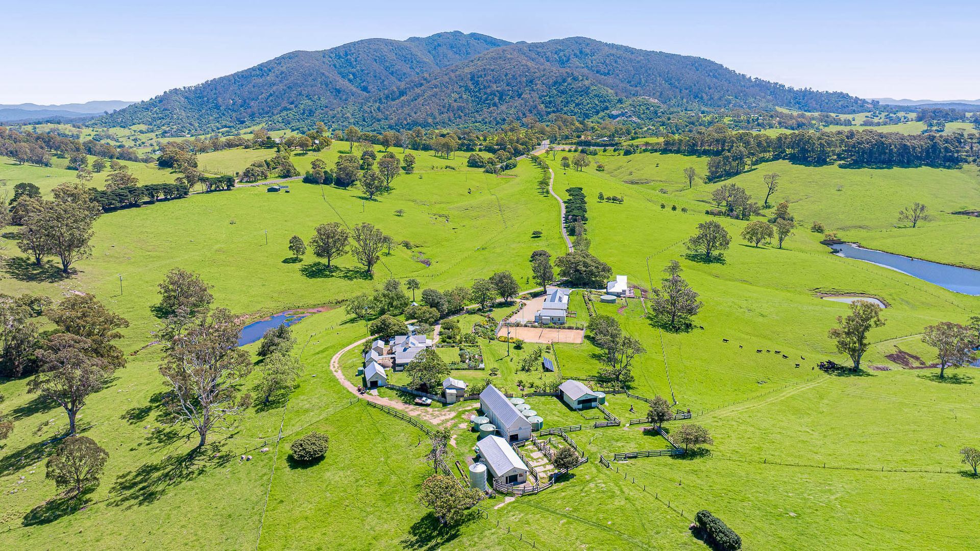 A rural property with multiple buildings, a winding path, and a lake.