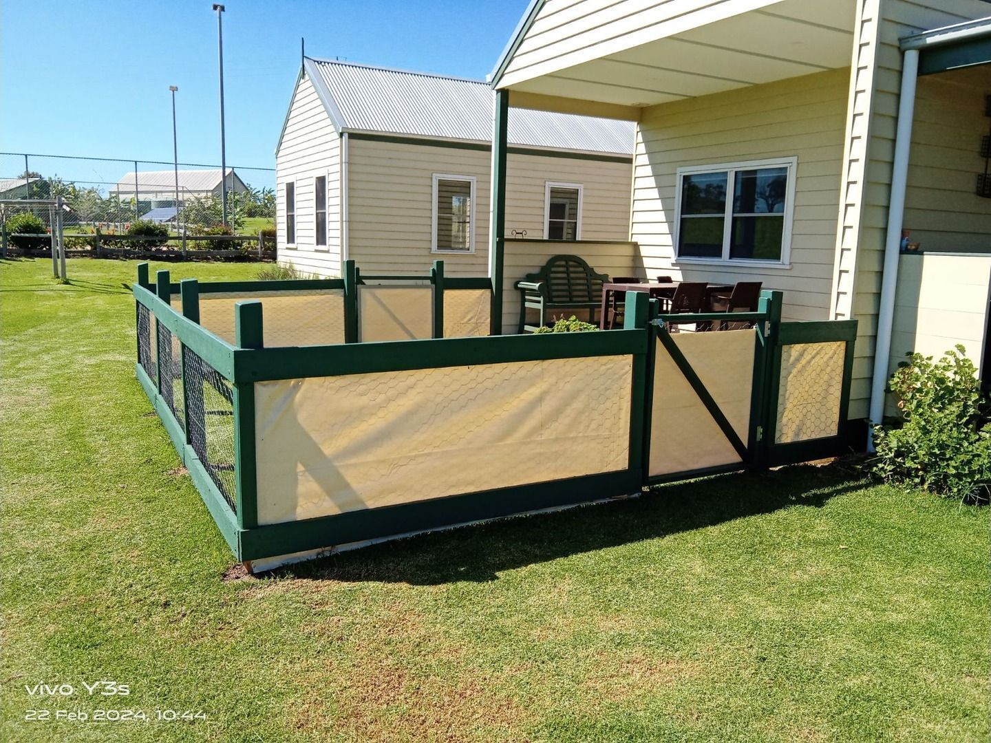 A fenced outdoor area with a building in the background.