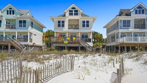 Une propriété située en bord de mer, comprenant plusieurs maisons, une plage de sable et une clôture en bois.