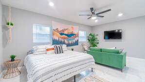 A modern bedroom with a bed, green sofa, and a TV.