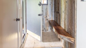 A hallway with a wooden bench, a gray rug, and a door leading to another room. - Outpost: White Ridge A6 (Teton Village)
