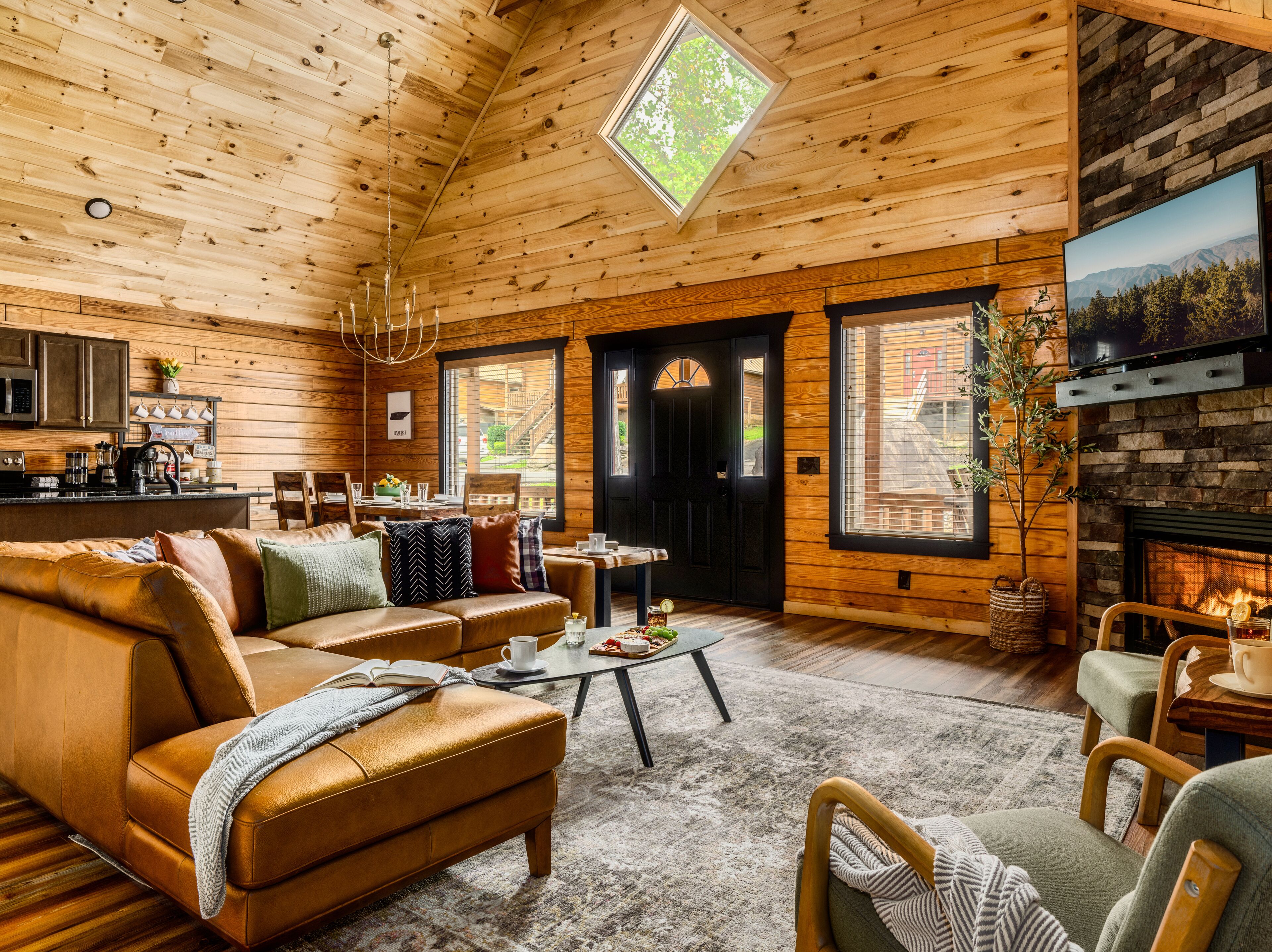 L’intérieur d’un chalet accueillant, avec un plafond en bois, une cheminée, un canapé, une table basse et un téléviseur.
