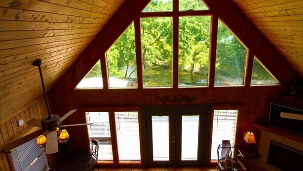 A wooden interior with a large window overlooking a forested area. - Create Memories this Spring Break | Smoky Waters (Sevierville)