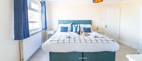 A bedroom with a bed, a bedside table, a window with curtains, and a ceiling light.