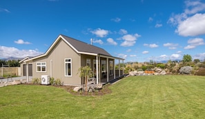 Een gelijkvloers huis met een overdekte veranda, een kleine tuin en een heldere lucht.
