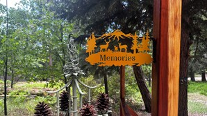 Escultura metálica con piñas y un cartel que dice 'Memories' en un parque.