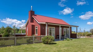 Une maison rouge avec un grand porche et une cheminée.