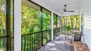 A covered porch with a view of lush greenery, a ceiling fan, and outdoor furniture. - Wiles Drive (Captiva)