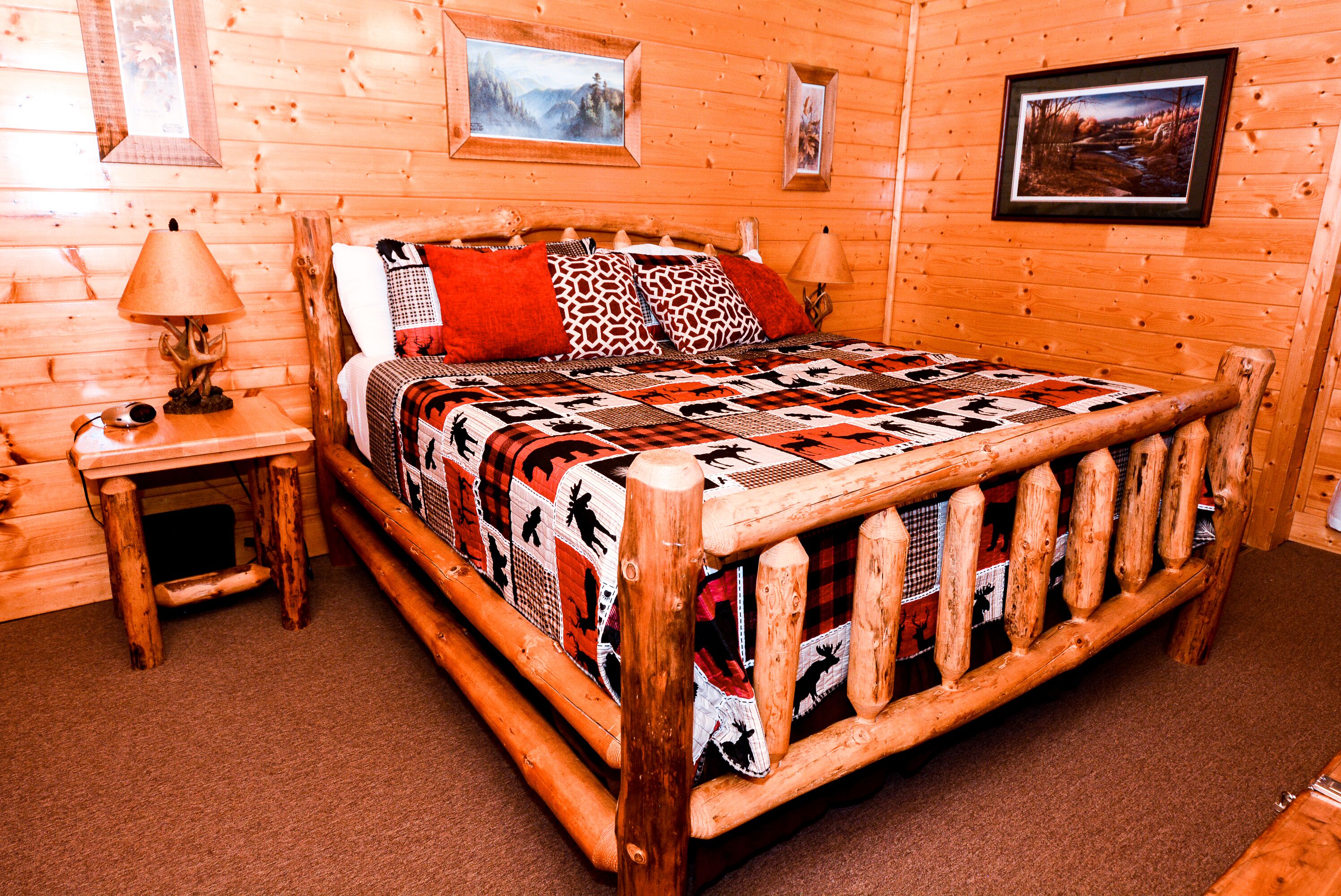 Une chambre à coucher de style cabane en bois, avec un lit, deux tables de chevet et une courtepointe.
