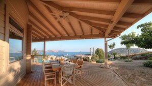 A wooden deck with a table and chairs, overlooking a pool and mountains. - LYCIPONON VILLA for an unforgettable, relaxing, private, and secure vacation (Ανάβυσσος)