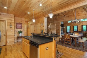 A wooden cabin interior with a kitchen, dining area, and a staircase. - Mtn Lodge~Hot Tub+Fire Pit+Fireplace, WiFi! (Burnsville)