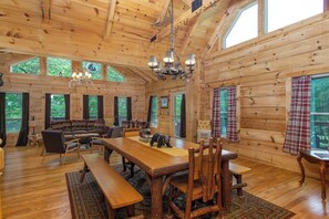 A log cabin interior with a wooden dining table, benches, and a sofa. - Mtn Lodge~Hot Tub+Fire Pit+Fireplace, WiFi! (Burnsville)