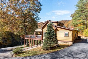 A log cabin with a porch, surrounded by trees with autumn foliage. - Mtn Lodge~Hot Tub+Fire Pit+Fireplace, WiFi! (Burnsville)