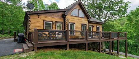 Een houten chalet met terras, omringd door bomen.
