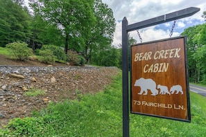 A wooden cabin sign with bear silhouettes and the name 'Bear Creek Cabin' along with the address '73 Fairchild Ln.'