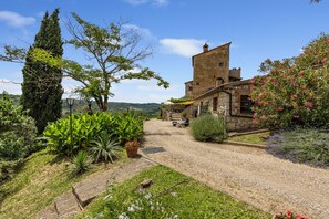 Un edificio rustico in pietra con un vialetto sterrato che conduce a una scala in legno.