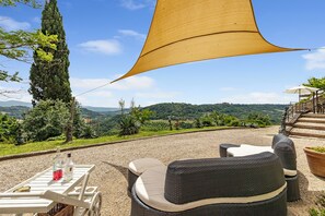 A patio with wicker furniture, a table with bottles, and a view of the countryside. - Torre Del Melograno With Heated Pool (Castiglione in Teverina)
