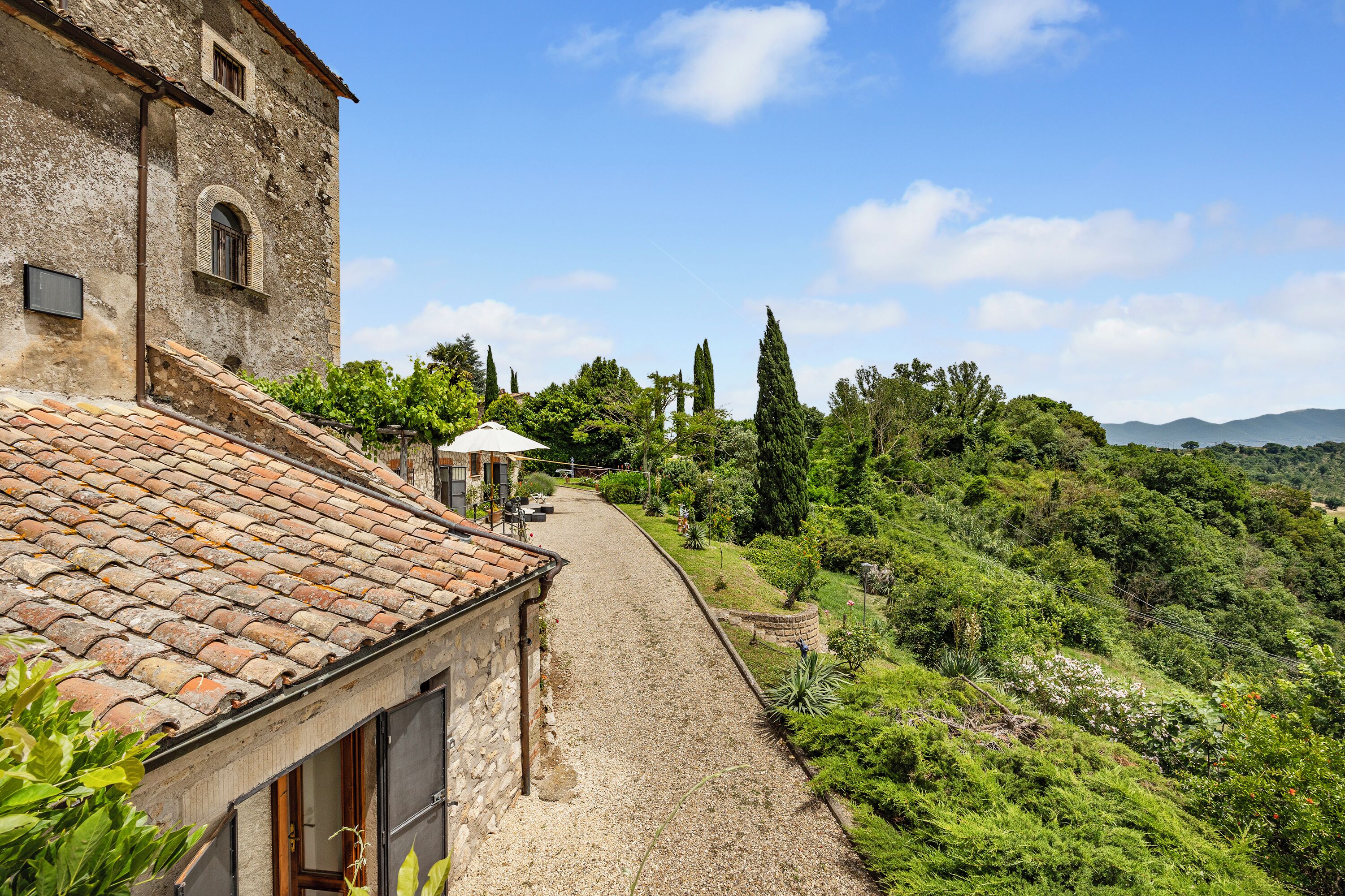 A narrow, cobblestone path leading to a stone building with a tiled roof.