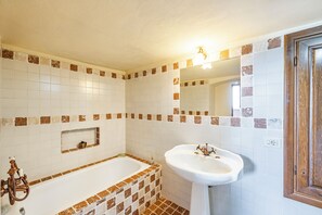 A bathroom with a bathtub, a sink, and a mirror. - Torre Del Melograno With Heated Pool (Castiglione in Teverina)