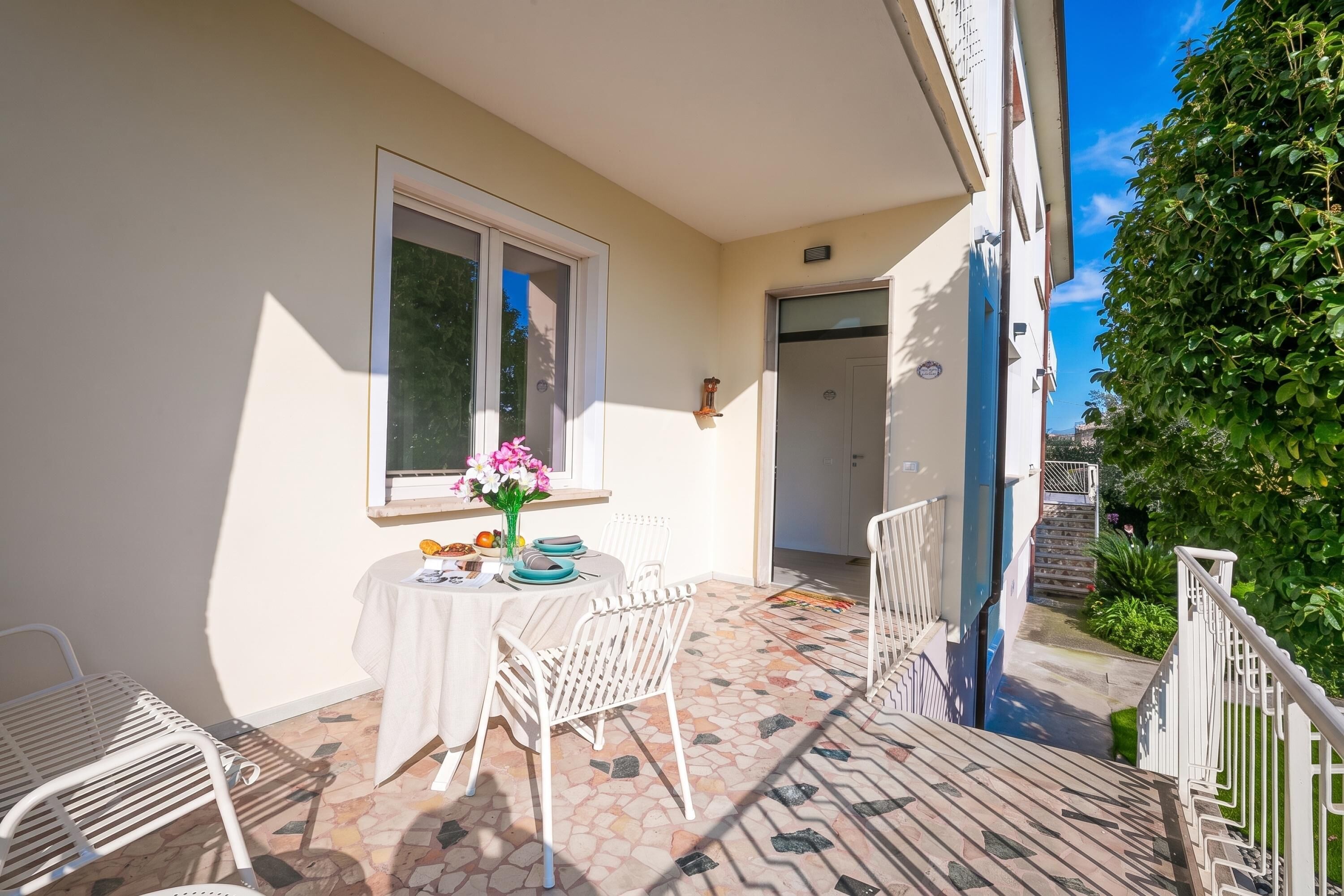 A balcony with a table and chairs, a window, and a door.