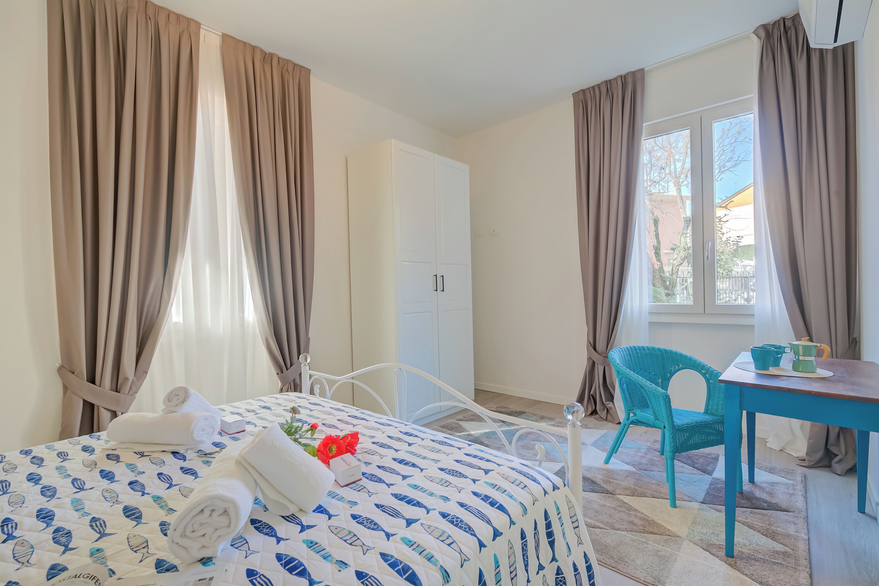 Une chambre d’hôtel avec un lit, un bureau, une chaise et une armoire.
