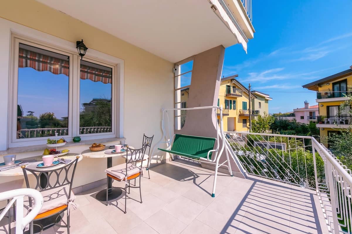 A balcony with a table, chairs, and a hanging chair.