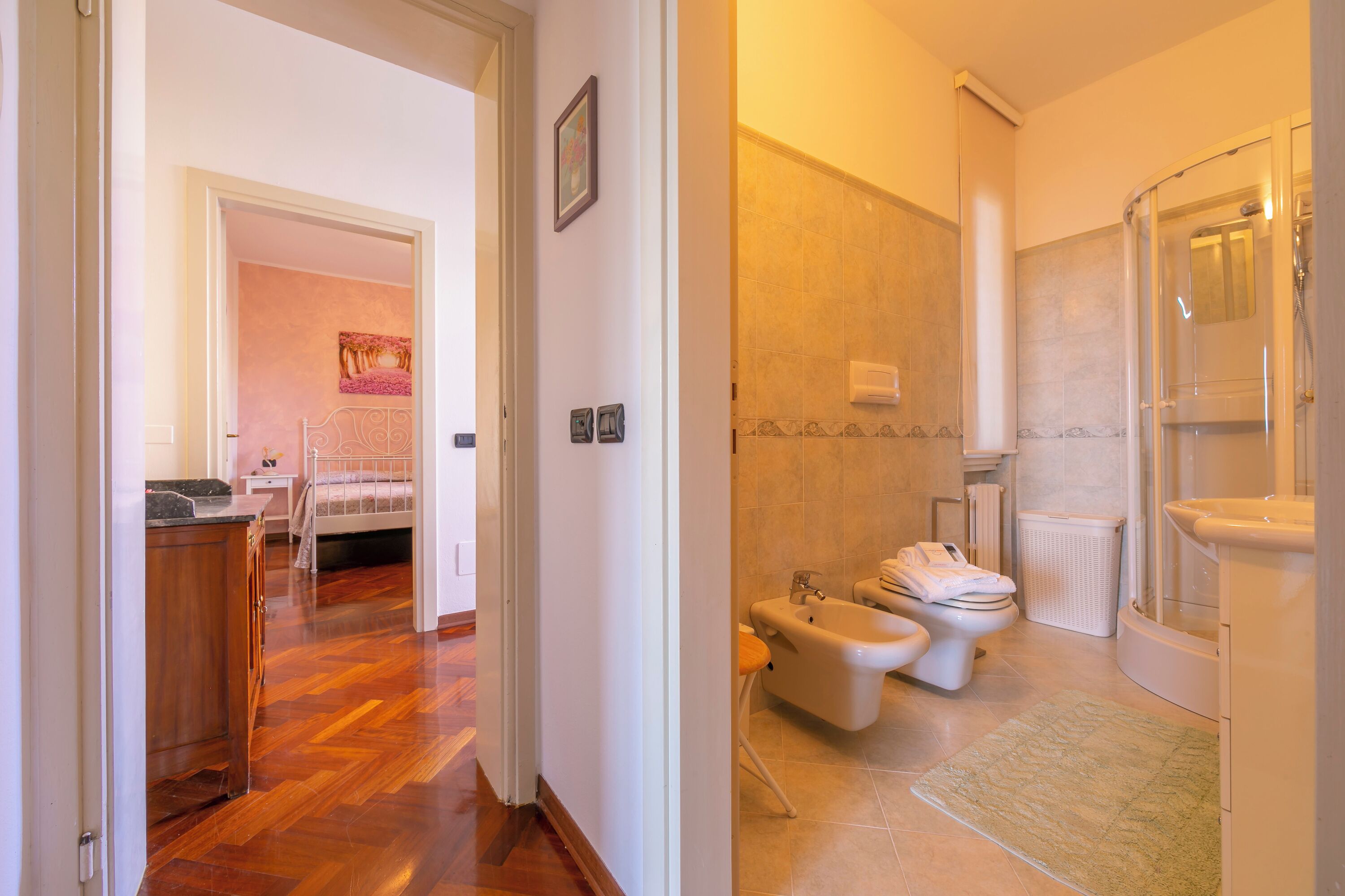 A bathroom with a shower, toilet, bidet, and a towel rack.
