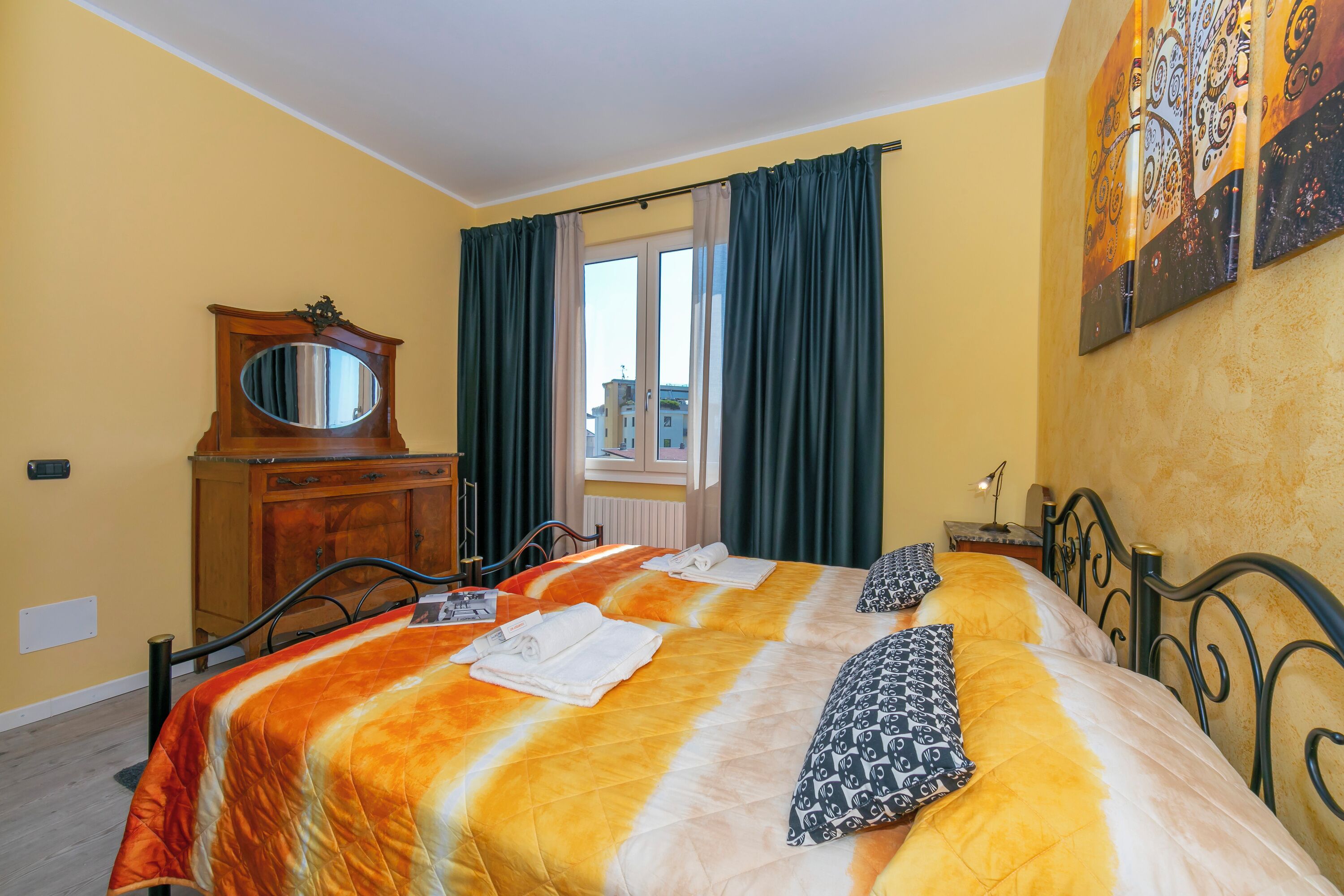 Una habitación de hotel con una cama, un tocador, un espejo y una ventana con cortinas.