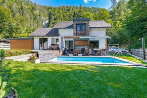 A modern two-story house with a swimming pool, a patio with outdoor furniture, and a forested backdrop. - Pool Villa Katja Near Kranjska Gora (Kranjska Gora)