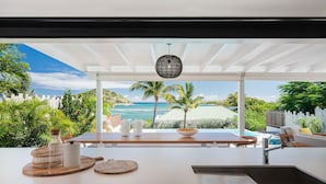 A modern outdoor dining area with a view of the ocean and palm trees. - A dream villa for an unforgettable vacation! (Cul-de-Sac)