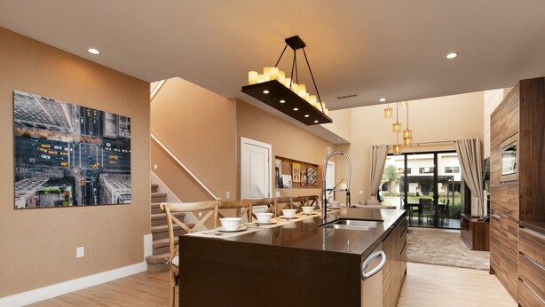 Een moderne keuken met een centraal eiland, houten vloeren en een trap naar een hoger niveau.