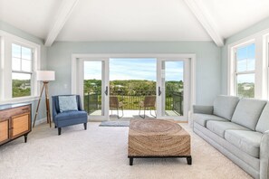 Un salon spacieux avec un balcon, un canapé, un fauteuil et une table basse.