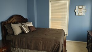 Un dormitorio con una cama, un aparador y una ventana con persianas.