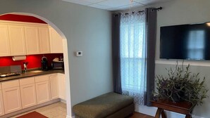 A compact living space with a kitchenette, a seating area, and a television. - White House Lodge-Lower Studio (Brookfield)
