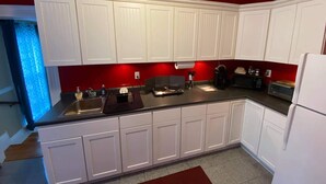 A kitchen with white cabinets, a black countertop, and a red accent wall. - White House Lodge-Lower Studio (Brookfield)
