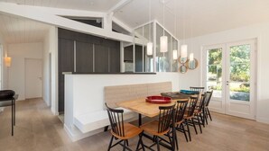 A modern kitchen with a wooden dining table, black chairs, and a bench. - Rialto - Magnificent architect's house sea view (Les Portes-en-Ré)