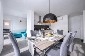 A modern dining area with a wooden table set for four, grey upholstered chairs, and a unique geometric pendant light. - Rustichel Fantastic Lake View (Toscolano Maderno)
