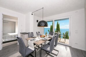 A dining area with a table set for four, a modern pendant light, and a balcony with a view of the sea. - Rustichel Fantastic Lake View (Toscolano Maderno)